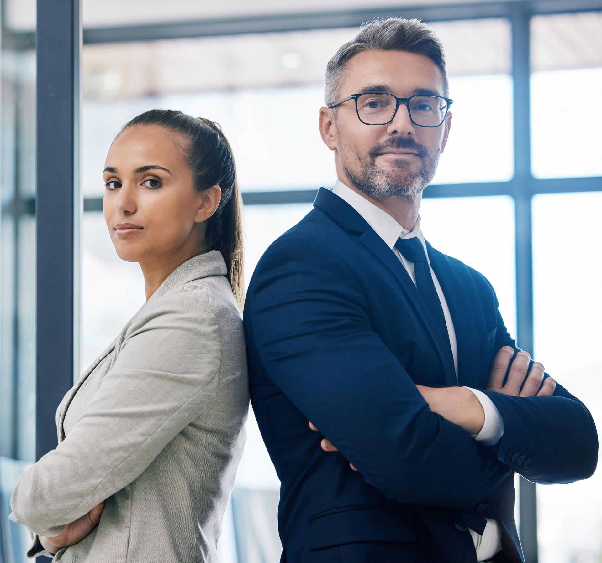 Partnership, arms crossed and teamwork with two business people standing together in corporate office building. Success, motivation and vision with employees in innovation or management company